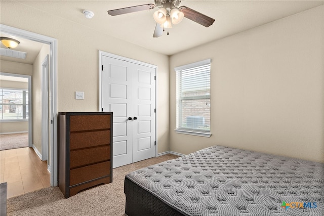 bedroom featuring ceiling fan, a closet, light carpet, and multiple windows