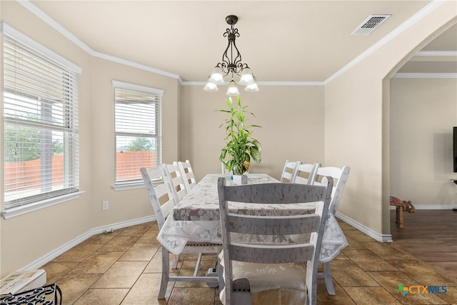 dining space with tile patterned floors, an inviting chandelier, and crown molding