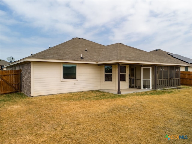 rear view of property featuring a yard, a patio, and a sunroom