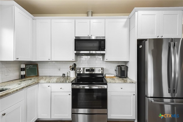 144 Slocum Dr, Canyon Lake, TX 78133 - kitchen featuring appliances with stainless steel finishes, white cabinets, tasteful backsplash, and light stone counters