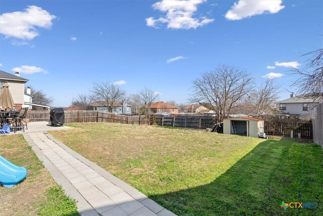view of yard with a storage unit, a fenced backyard, a patio, and an outdoor structure