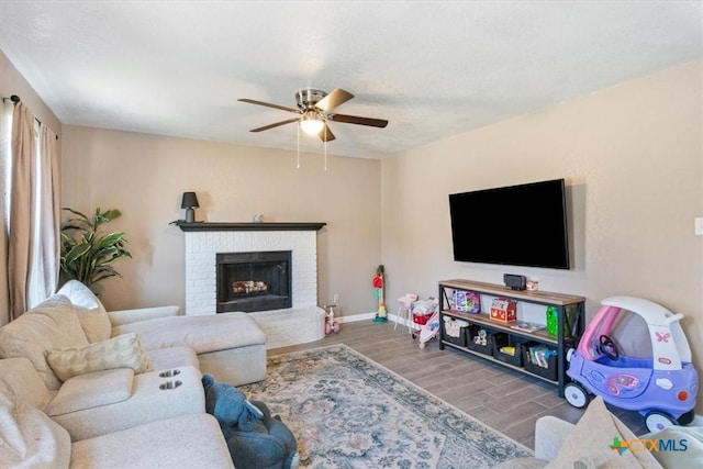 living room featuring wood-type flooring, a brick fireplace, and ceiling fan