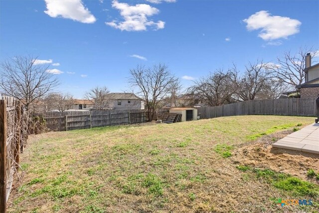 view of yard featuring a fenced backyard, a storage unit, and an outbuilding