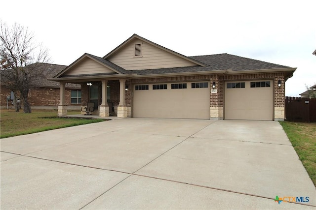 view of front of house with brick siding, an attached garage, a shingled roof, and driveway