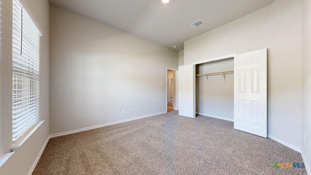 unfurnished bedroom with carpet floors, vaulted ceiling, and a closet