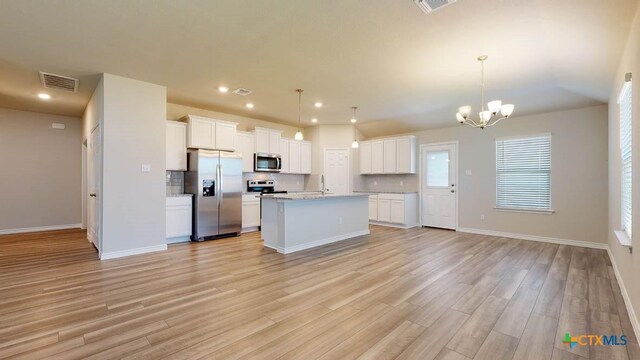 kitchen featuring white cabinetry, light hardwood / wood-style floors, decorative light fixtures, and appliances with stainless steel finishes