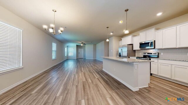 kitchen featuring white cabinets, ceiling fan with notable chandelier, hanging light fixtures, light hardwood / wood-style flooring, and stainless steel appliances