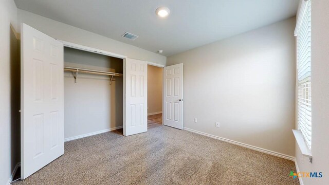 unfurnished bedroom with carpet, a closet, and multiple windows