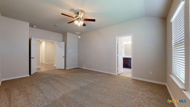 unfurnished bedroom with ensuite bath, ceiling fan, light colored carpet, and lofted ceiling