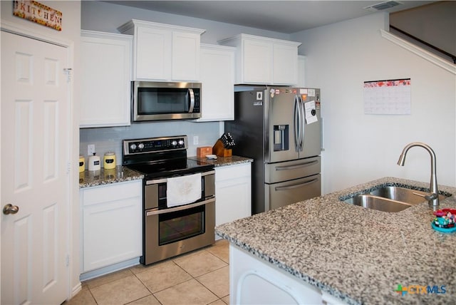 8915 Stonehollow Dr, Temple, TX 76502 - kitchen featuring appliances with stainless steel finishes, a sink, white cabinets, light stone countertops, and light tile patterned flooring