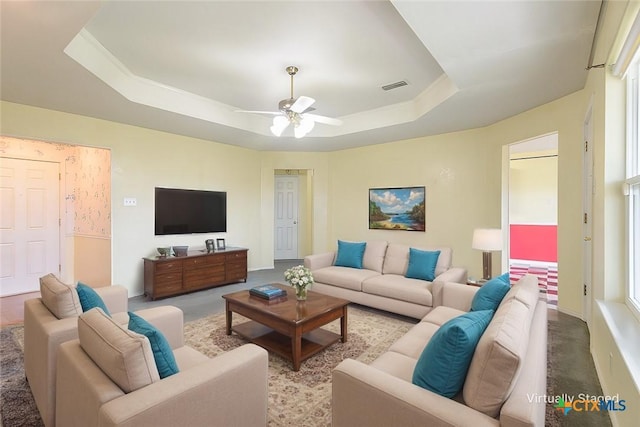 carpeted living area featuring a ceiling fan, a tray ceiling, and visible vents