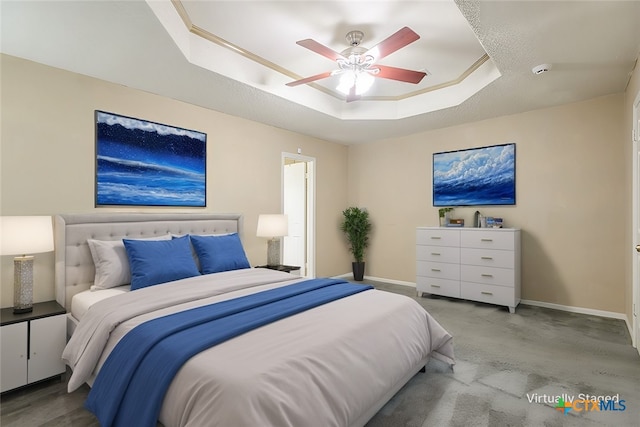 bedroom with carpet floors, a tray ceiling, a ceiling fan, and baseboards