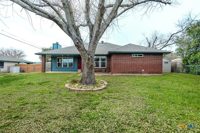 back of house with a fenced backyard, brick siding, roof with shingles, a lawn, and a chimney