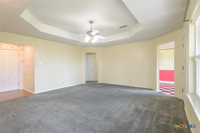 unfurnished room with a tray ceiling, carpet flooring, and visible vents