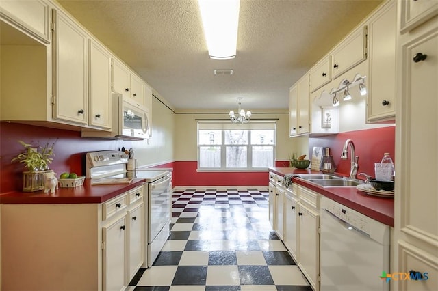 kitchen featuring dark floors, dark countertops, visible vents, a sink, and white appliances