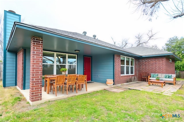 rear view of house featuring a patio, roof with shingles, a yard, outdoor lounge area, and brick siding