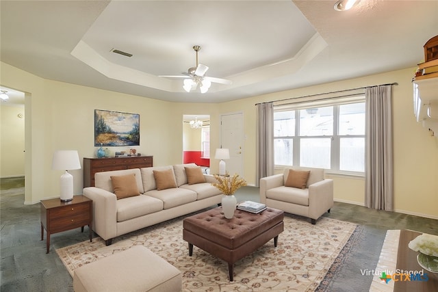 living room with baseboards, visible vents, a raised ceiling, and a ceiling fan