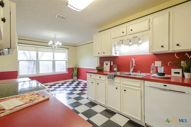 kitchen with a textured ceiling, white dishwasher, a sink, visible vents, and tile patterned floors