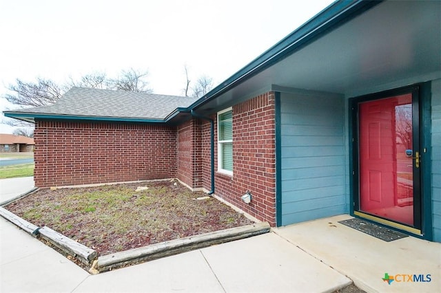 property entrance with brick siding and roof with shingles