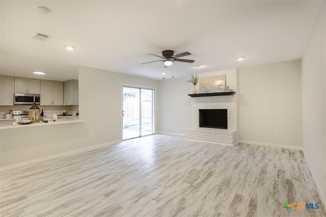 unfurnished living room featuring ceiling fan, a fireplace, and light hardwood / wood-style flooring