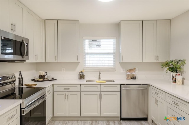 kitchen featuring appliances with stainless steel finishes, sink, and white cabinets