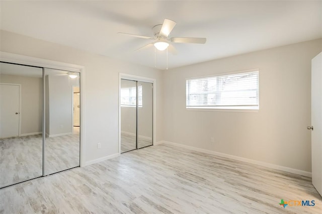 unfurnished bedroom with two closets, light hardwood / wood-style flooring, and ceiling fan