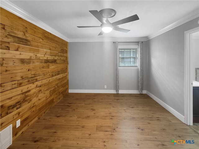 unfurnished room with wood walls, light hardwood / wood-style floors, ceiling fan, and ornamental molding