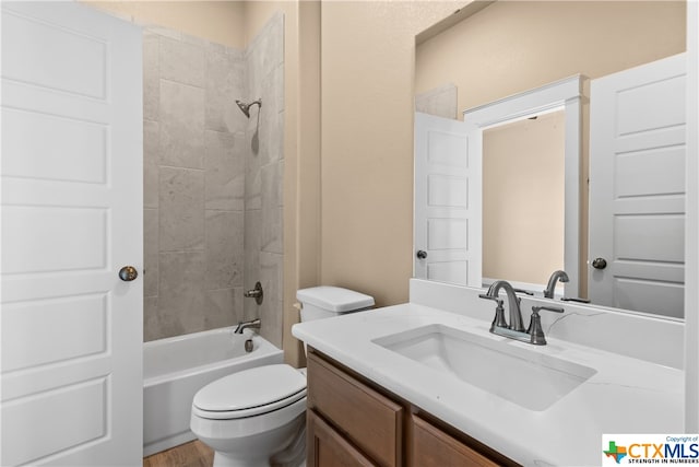 full bathroom featuring toilet, tiled shower / bath combo, and vanity