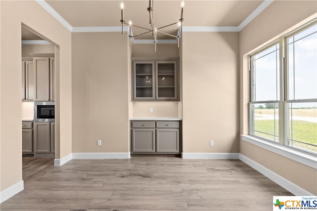 unfurnished dining area featuring ornamental molding, light wood-type flooring, and a chandelier