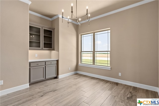 unfurnished dining area with ornamental molding, light hardwood / wood-style flooring, and a notable chandelier