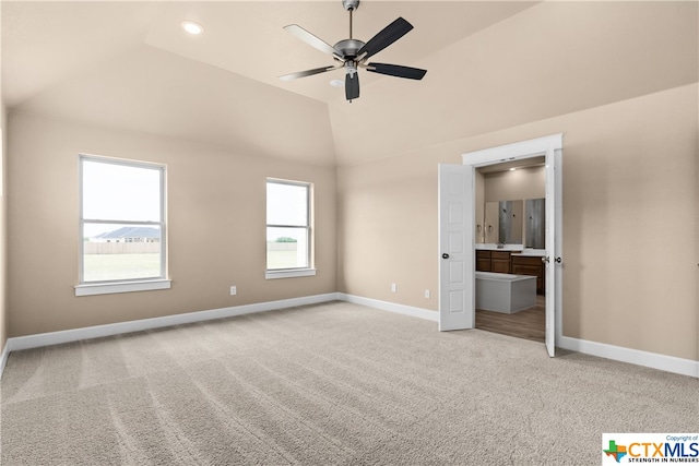 unfurnished bedroom with ensuite bathroom, light colored carpet, ceiling fan, and vaulted ceiling