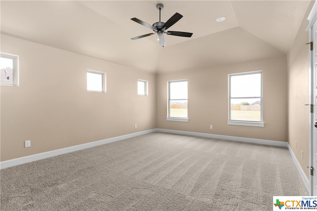 carpeted spare room with ceiling fan, vaulted ceiling, and a healthy amount of sunlight