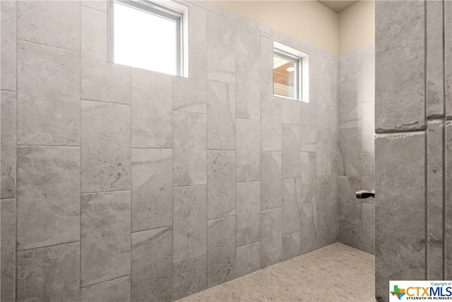 bathroom featuring a tile shower and a healthy amount of sunlight