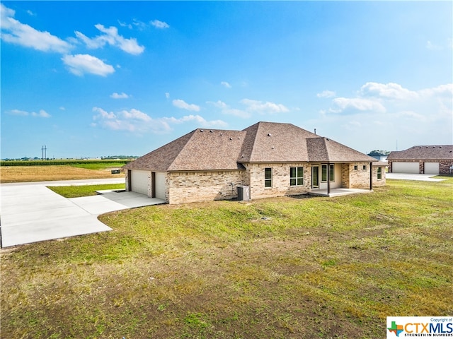 rear view of house with a lawn, central AC, and a garage