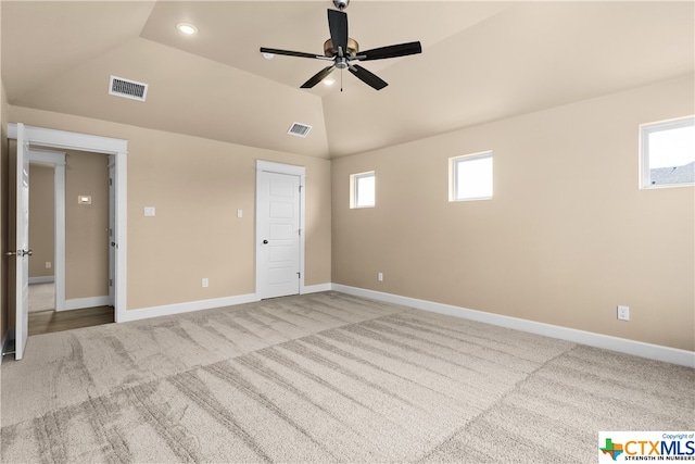 unfurnished bedroom featuring ceiling fan, multiple windows, vaulted ceiling, and light colored carpet