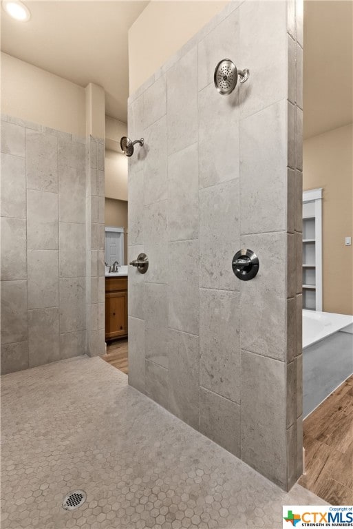 bathroom featuring wood-type flooring, sink, and a tile shower