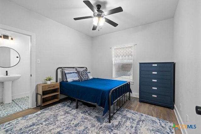 bedroom with dark wood-type flooring, ceiling fan, sink, and ensuite bath