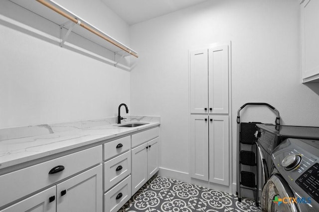 clothes washing area with sink, light tile patterned floors, cabinets, and washing machine and clothes dryer