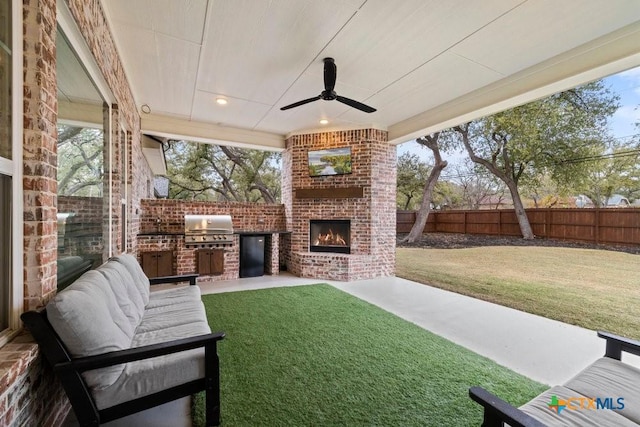 view of patio / terrace featuring an outdoor brick fireplace, an outdoor kitchen, a grill, and ceiling fan