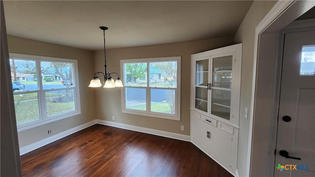 unfurnished dining area featuring dark wood-type flooring and an inviting chandelier