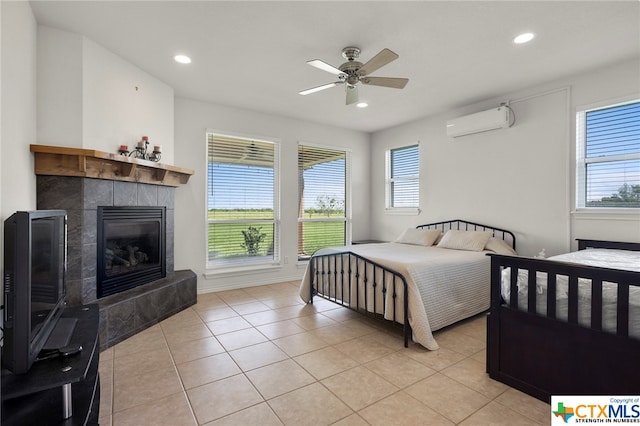 tiled bedroom with ceiling fan, multiple windows, a tile fireplace, and an AC wall unit