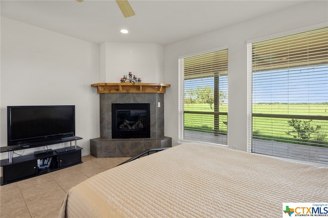 bedroom featuring a tile fireplace, ceiling fan, and light tile patterned flooring