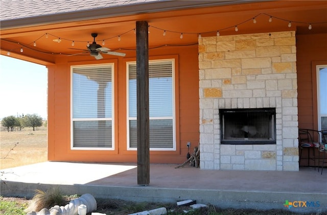 view of patio / terrace featuring ceiling fan and an outdoor stone fireplace