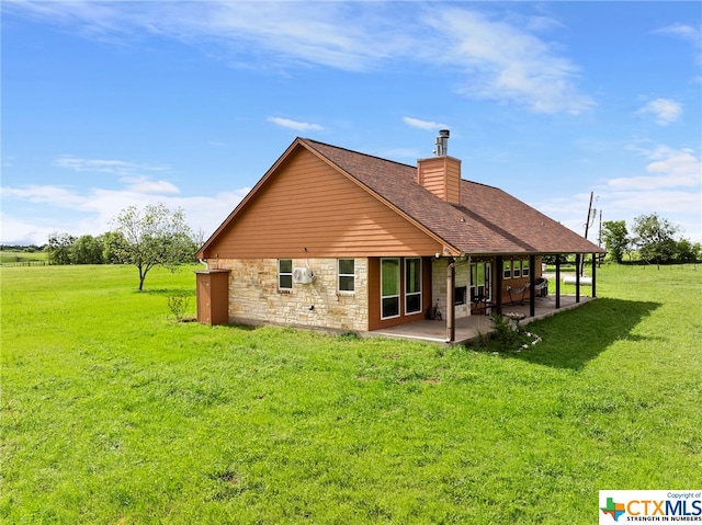 rear view of property with a rural view, a lawn, and a patio