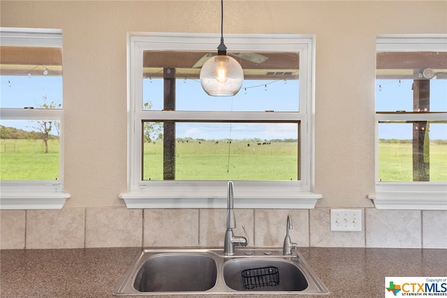 kitchen featuring a rural view, sink, and decorative light fixtures