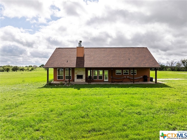 back of property with a rural view and a yard