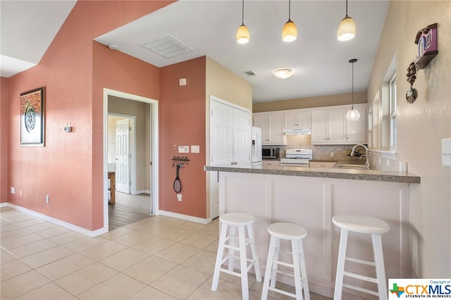 kitchen featuring white cabinetry, backsplash, light tile patterned floors, kitchen peninsula, and white appliances