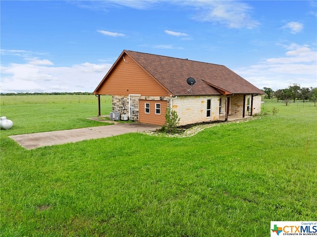 back of house with a rural view, a yard, and central AC