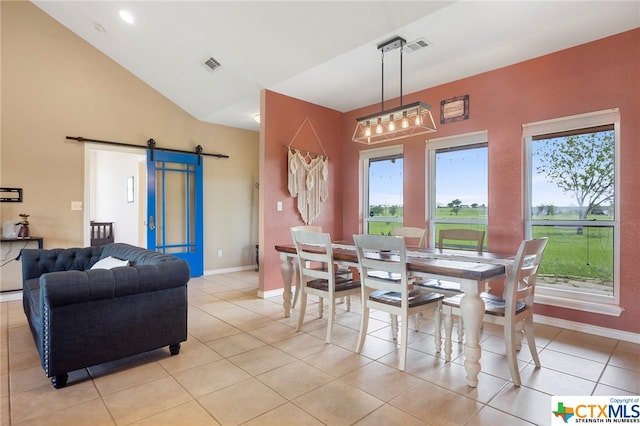 dining space featuring lofted ceiling, a barn door, and light tile patterned floors