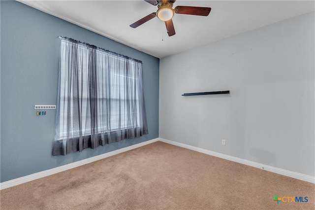 carpeted empty room featuring baseboards and a ceiling fan